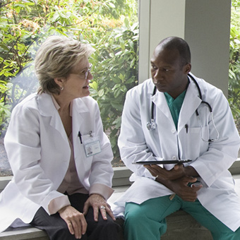 Two medical professionals talking to each other while sitting